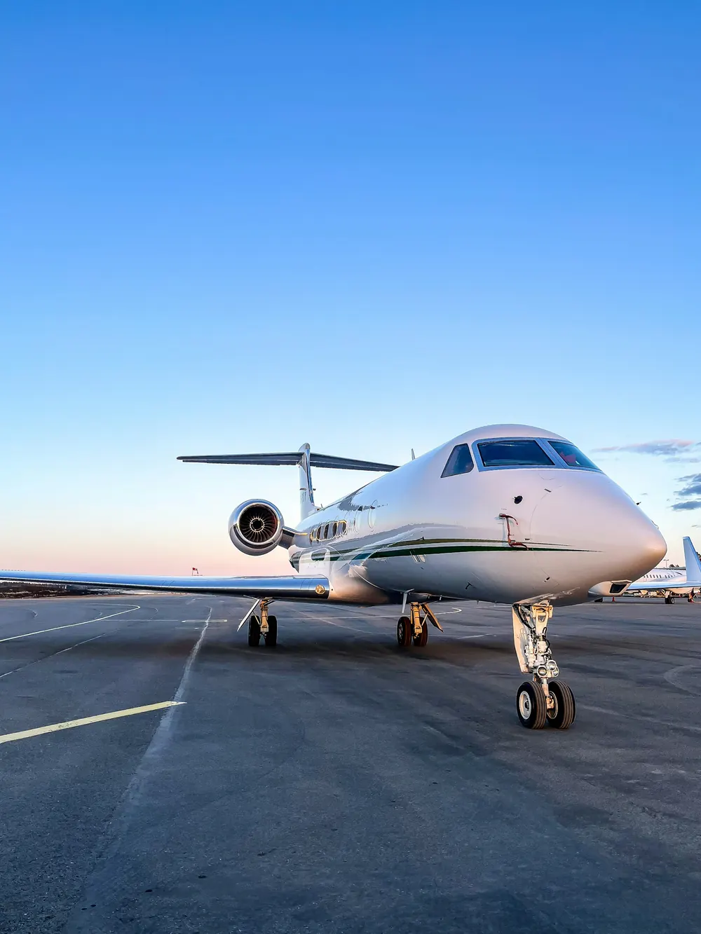 A white Gulfstream business jet parked on the ramp under a clear blue sky